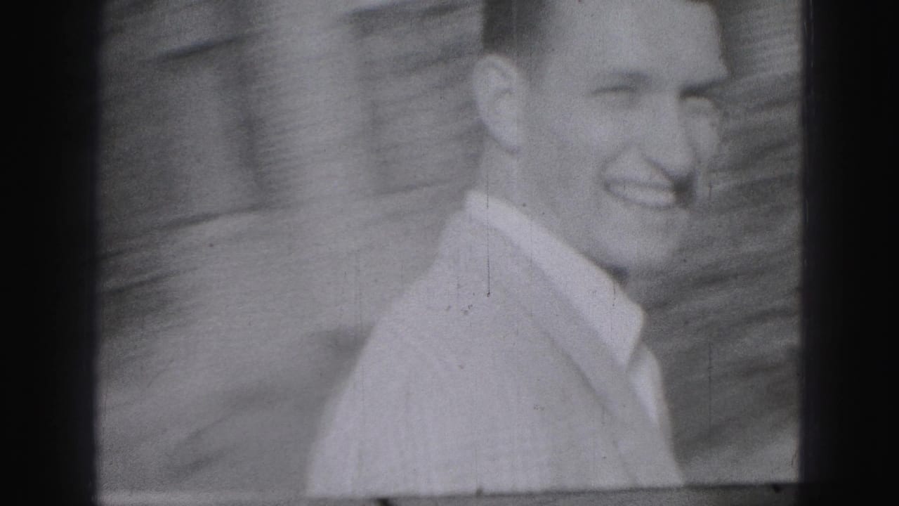 In 1946 Harrisburg home-movie footage, a smiling young man in a light collared shirt stands or walks near a masonry wall.
