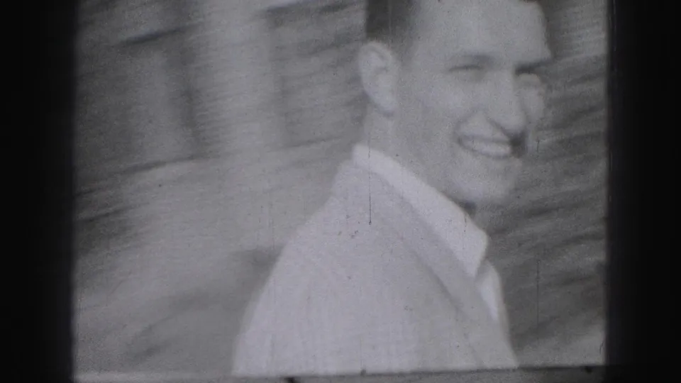 In 1946 Harrisburg home-movie footage, a smiling young man in a light collared shirt stands or walks near a masonry wall.