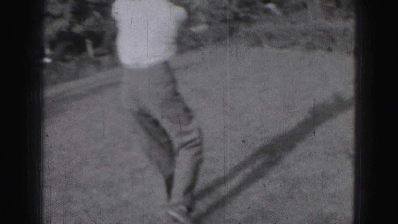 Golfer on a lawn seen mid-motion beside a dark film border.