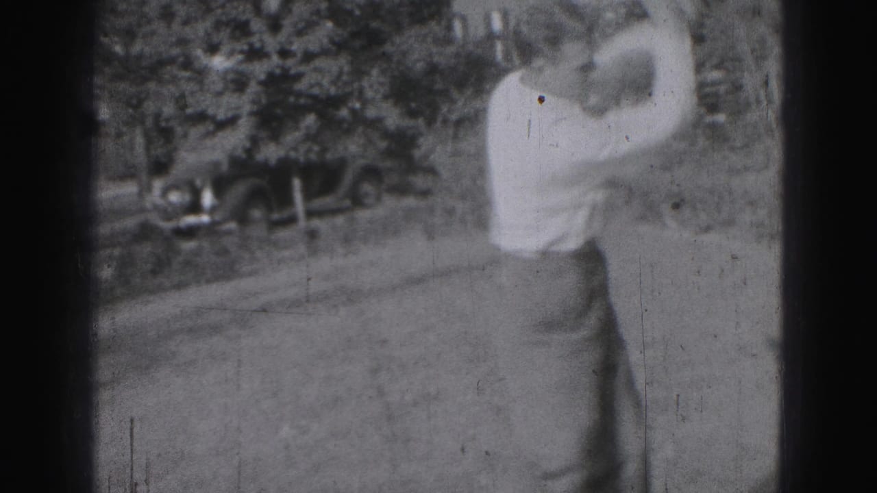 Adult man plays golf on a grassy course near Harrisburg in 1946, with a vintage car partly visible behind trees.