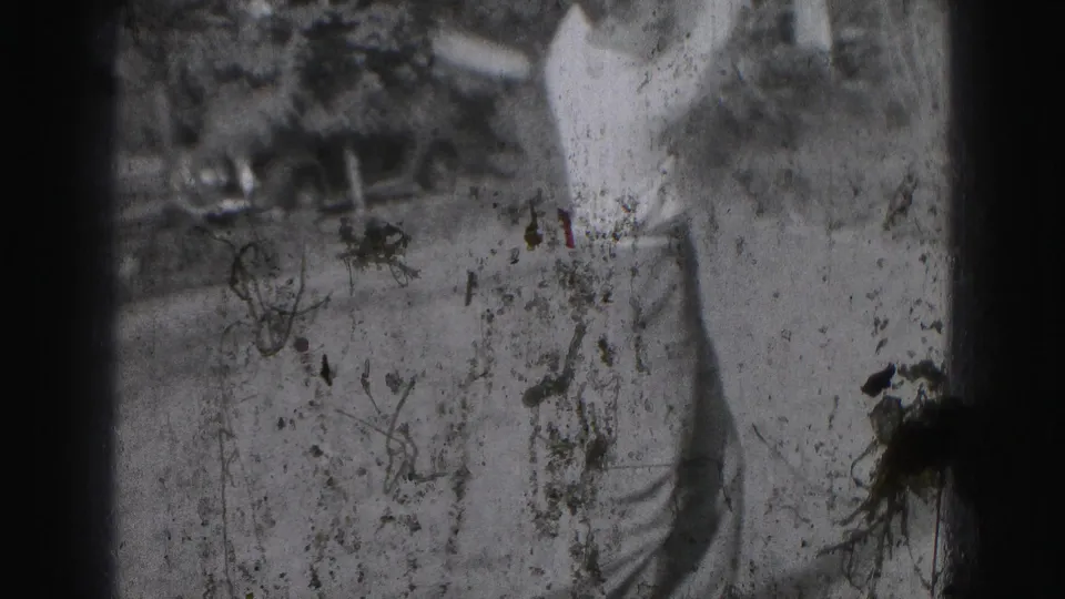 Motion-blurred 1946 home-movie frame shows the golfer during a swing, with grass, trees, and a parked car partly visible.
