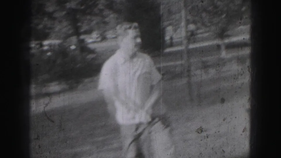 Adult man on a 1946 Harrisburg grass course holds a golf club after a swing, framed in soft black-and-white 8mm footage.
