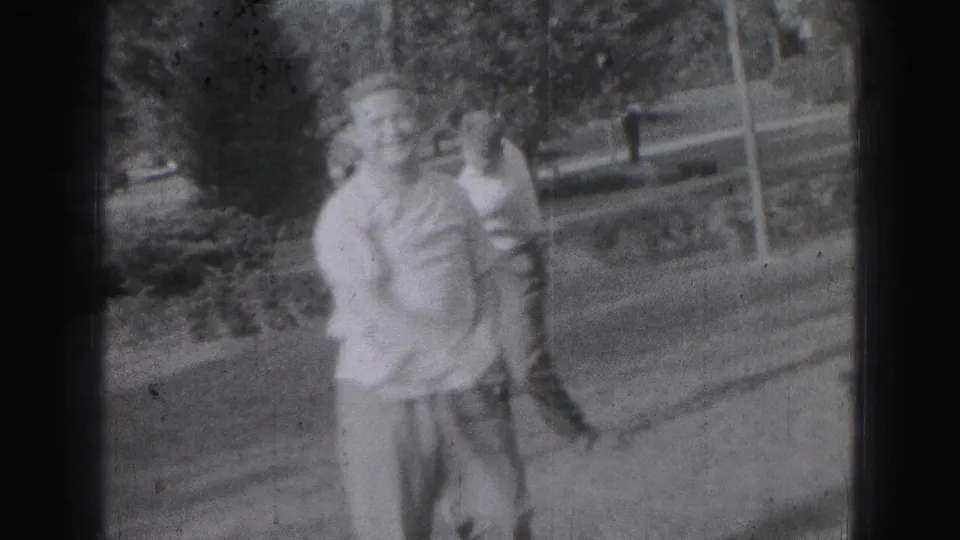 Two young men in 1946 Harrisburg stand together in a park-like outdoor setting, one holding a golf club.