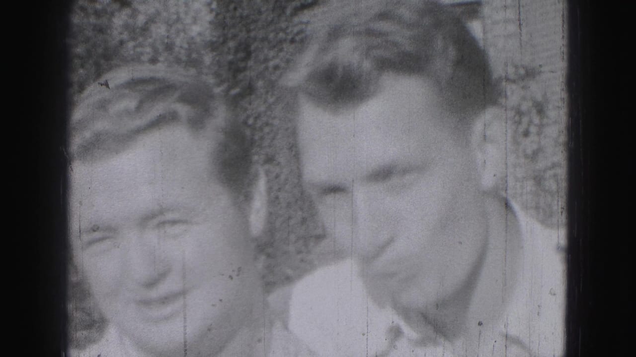 Two adult men in light shirts smile or lean toward the camera in 1946 Harrisburg home-movie footage.