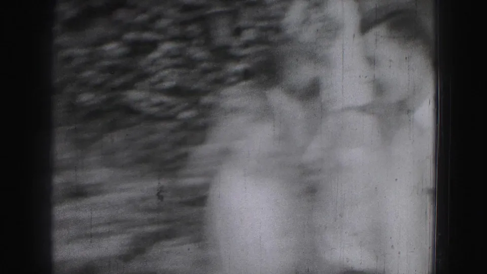 A blurred 1946 Harrisburg home-movie frame shows partial figures of young men moving near a leafy outdoor backdrop.