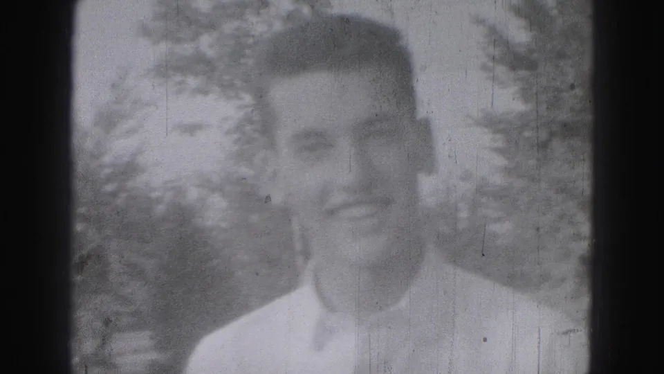 Soft-focus 1946 Harrisburg home-movie frame showing an adult man in a light shirt against leafy outdoor background.
