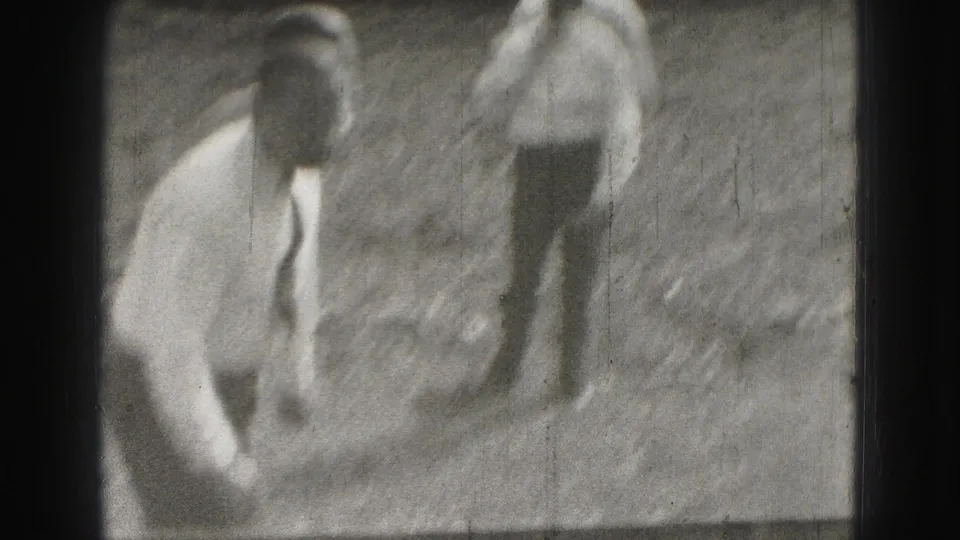 Two adult men appear outdoors in Harrisburg 1946, with one crouched or bending near the ground and the other standing behind him.