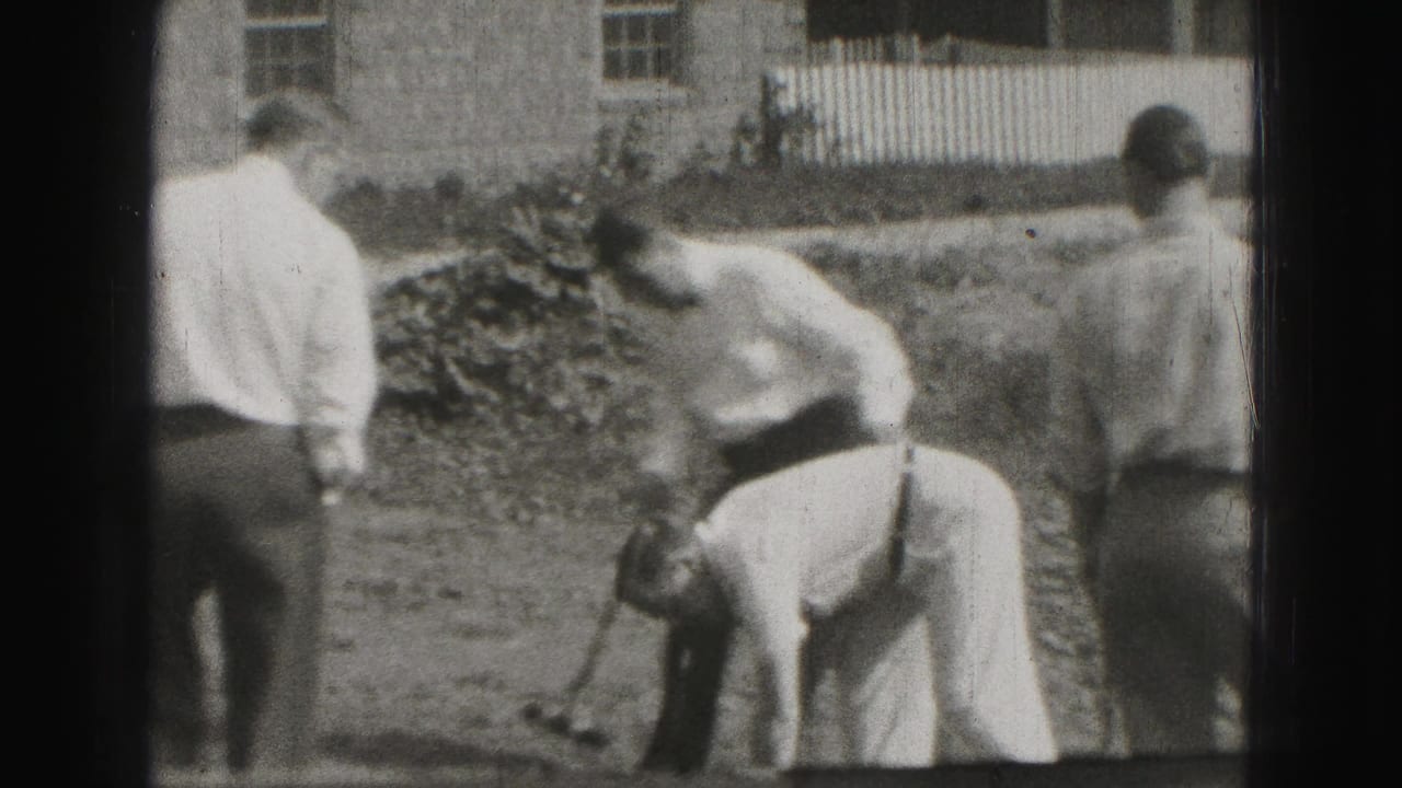 1946 Harrisburg home-movie frame showing men in dress shirts and trousers gathered around a backyard croquet shot.