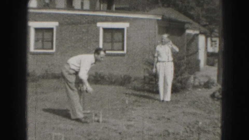A man leans over a croquet shot while another watches near a brick house in Harrisburg, Pennsylvania, 1946.