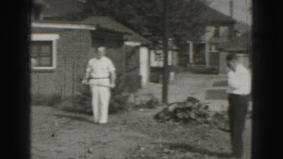 Home-movie frame from the 1946 Harrisburg croquet scene, with men spaced across a residential backyard.