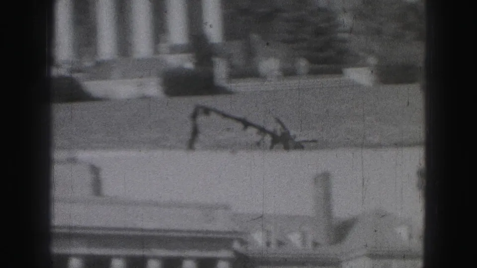 Soft 8mm black-and-white frame from the 1946 Harrisburg clip showing a columned building facade, ledge details, and heavy dark edge vignetting.