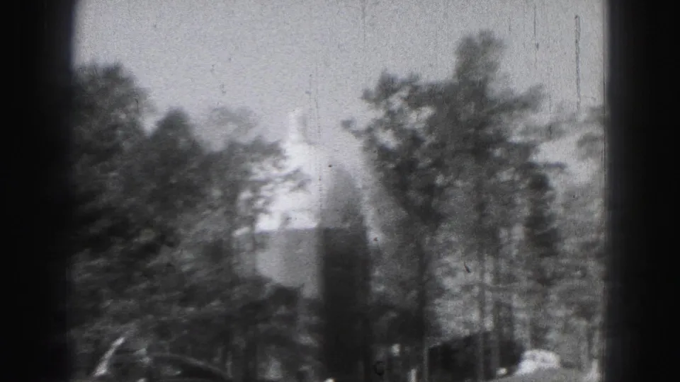 1946 Harrisburg home-movie frame showing trees and a distant domed building partly obscured by foliage.