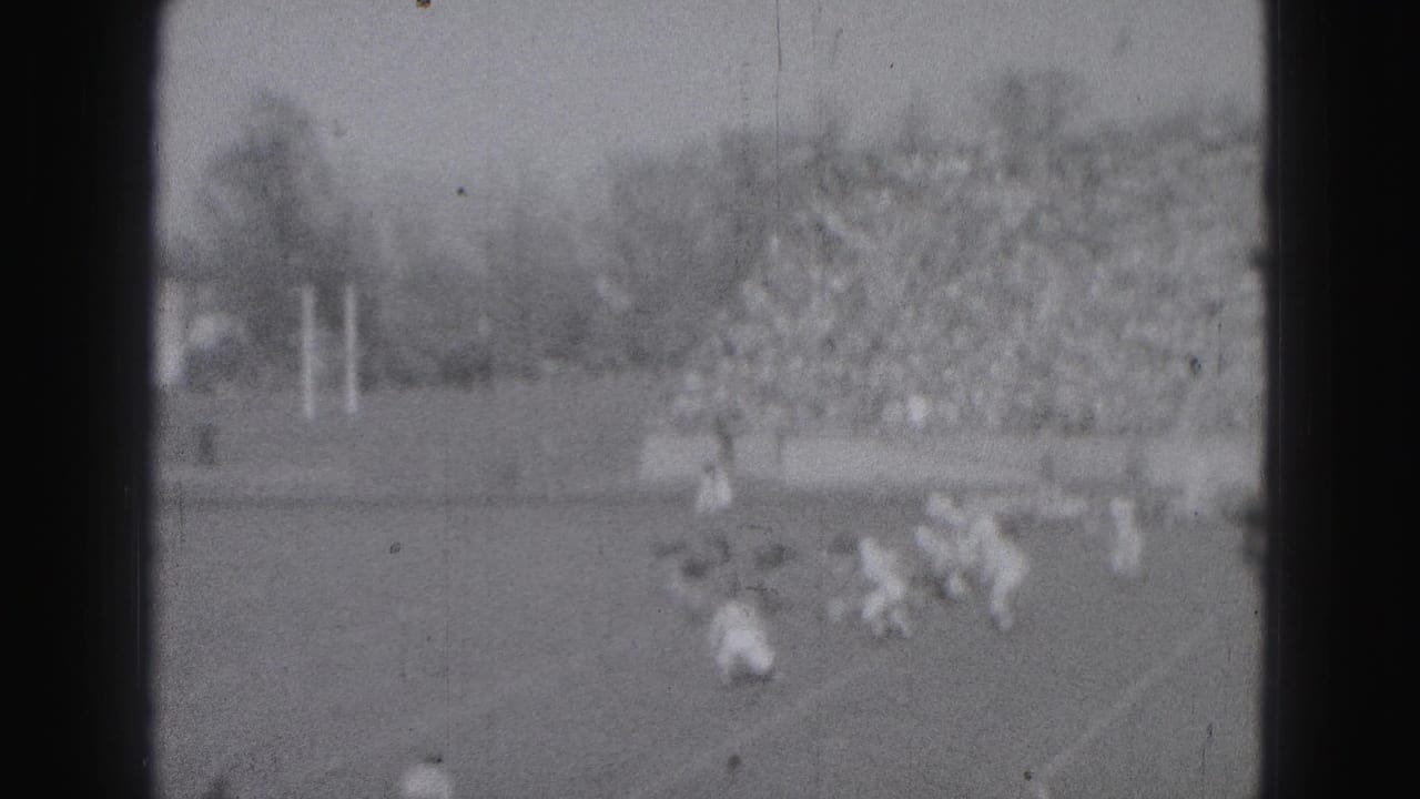 1946 Harrisburg football game footage showing players converging on a play before a packed stadium crowd.