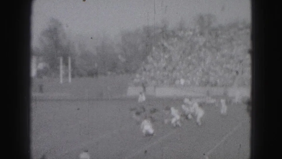 1946 Harrisburg football game footage showing players converging on a play before a packed stadium crowd.