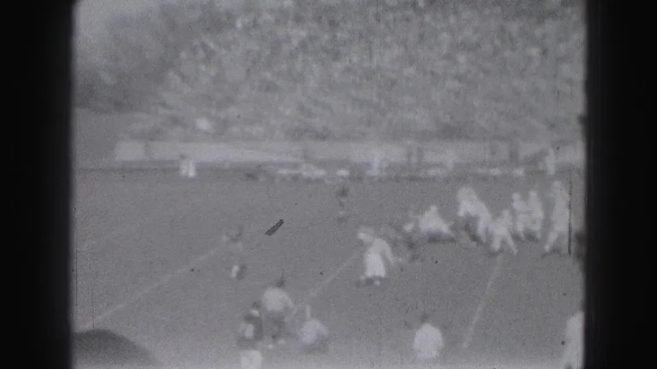 1946 Harrisburg home-movie football frame showing players scattered after a play, with grandstands and field markings visible.