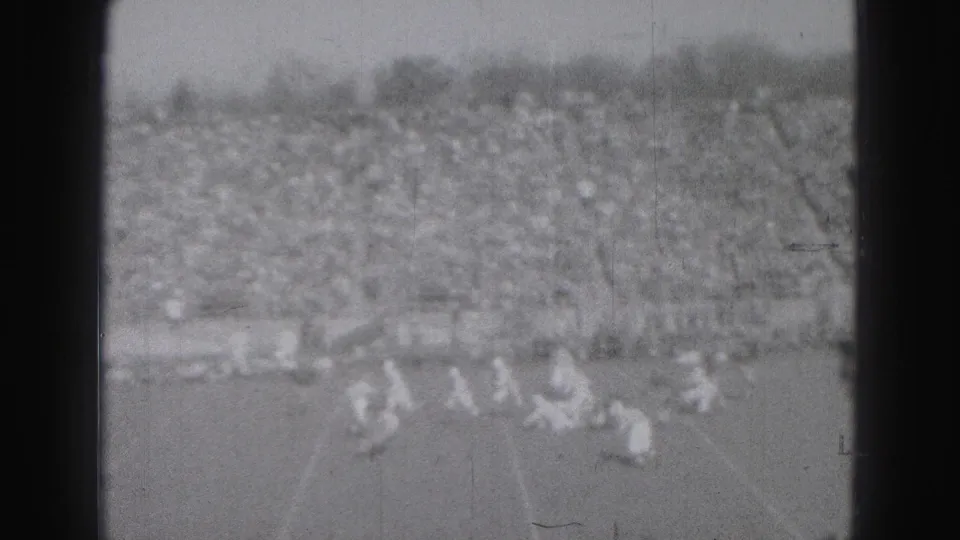 Wide 1946 Harrisburg stadium view with small figures on the football field and densely occupied bleachers in the background.