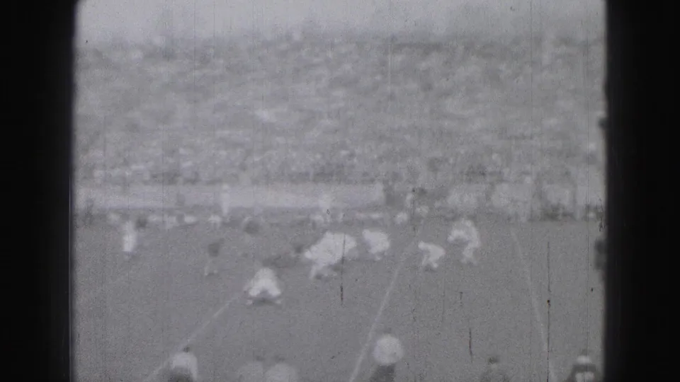 Late-frame view of the 1946 Harrisburg football game, showing players spread across the field and distant spectators.