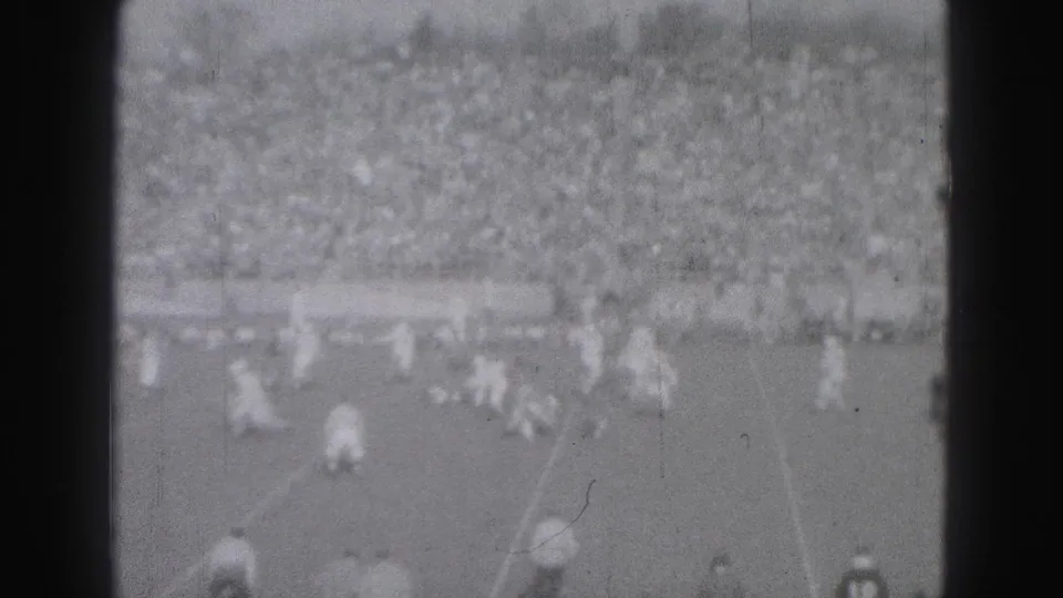 1946 Harrisburg home-movie frame showing distant field play before a packed stadium crowd.