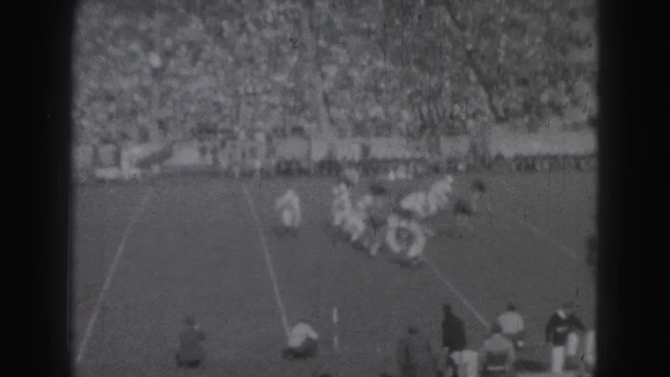 1946 Harrisburg football game scene with players converging near midfield, sideline figures below, and a large crowd in the background.