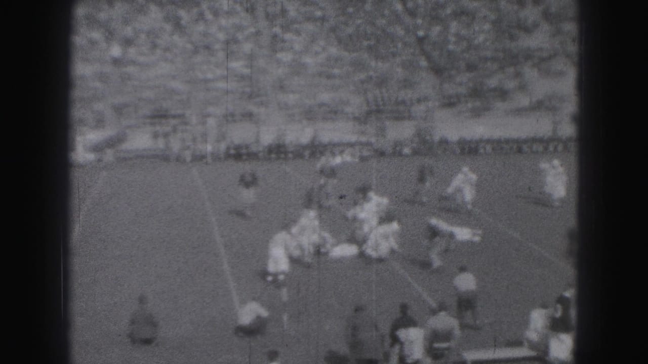 Players in light and dark uniforms cluster during a play on the field.