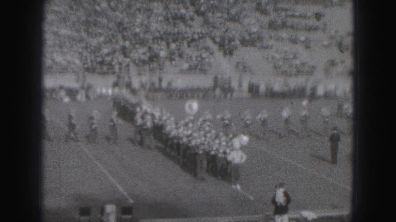 A marching band forms a diagonal line across a football field.