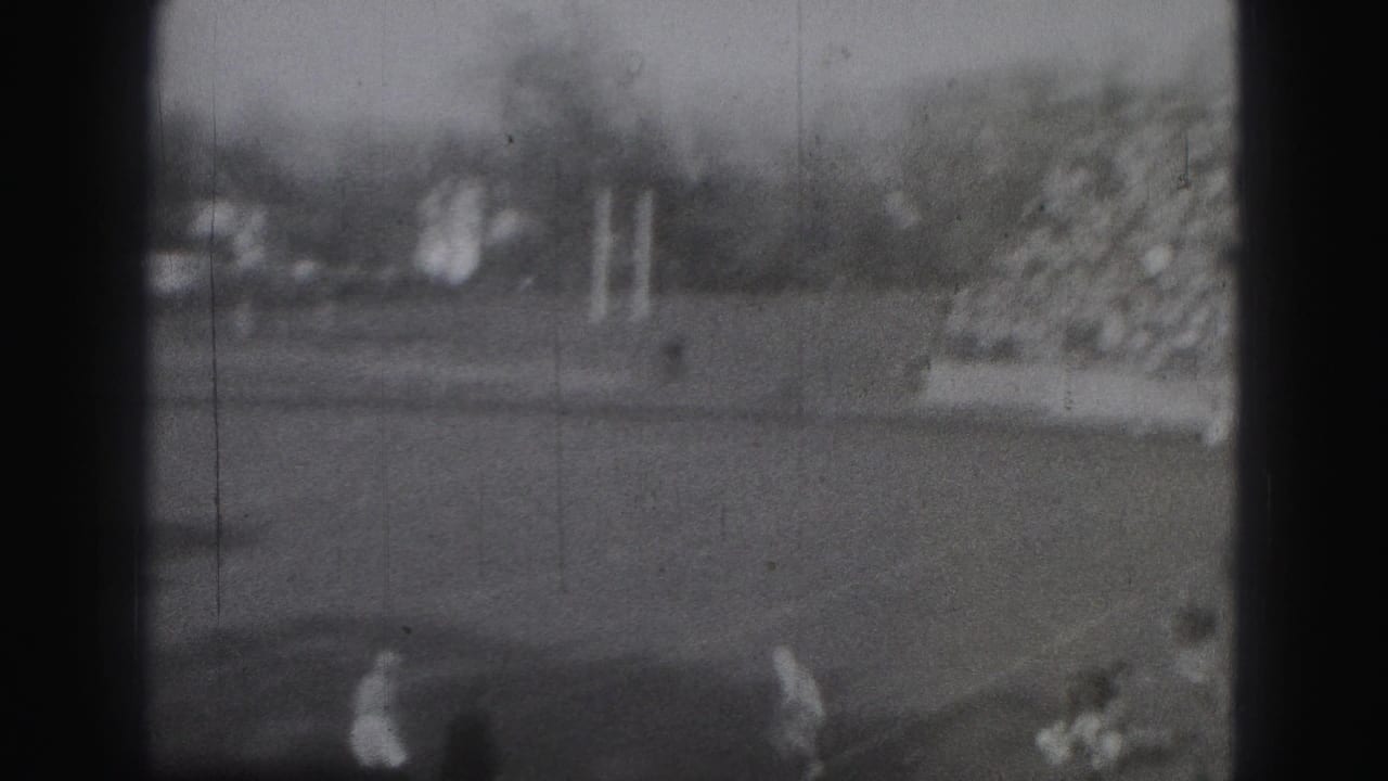 1946 Harrisburg home-movie frame showing distant rugby players on a field, with soft focus, grain, and dark 8mm frame edges.