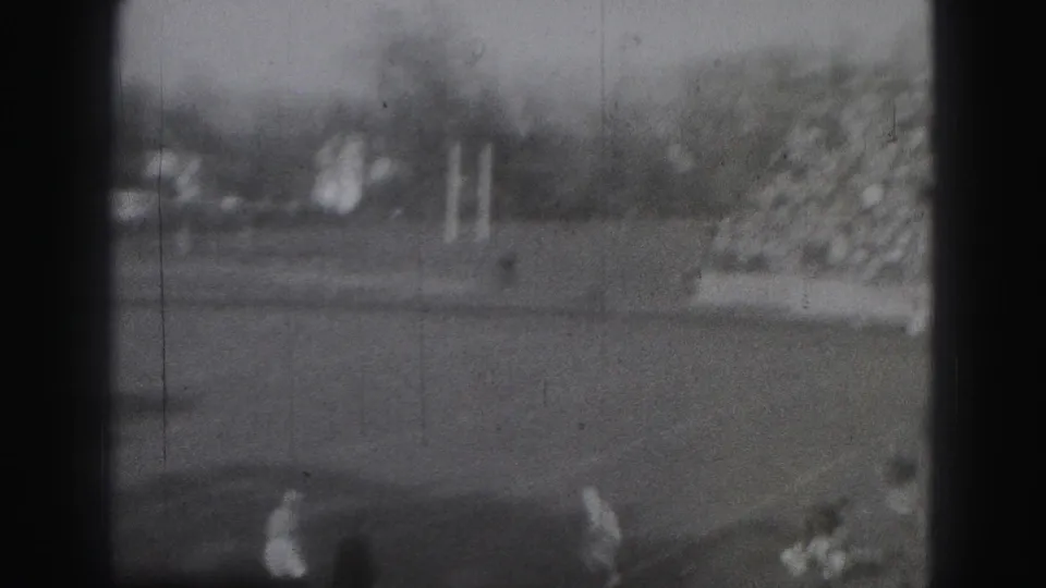 1946 Harrisburg home-movie frame showing distant rugby players on a field, with soft focus, grain, and dark 8mm frame edges.