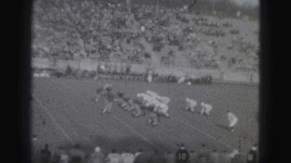 1946 Harrisburg rugby action with a cluster of players near the ground and a large spectator crowd in the background.