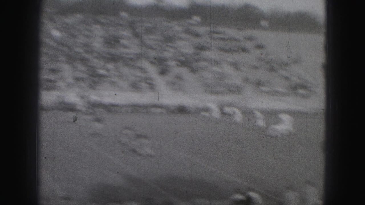 Distant football field seen through dark frame edges with players near the center.
