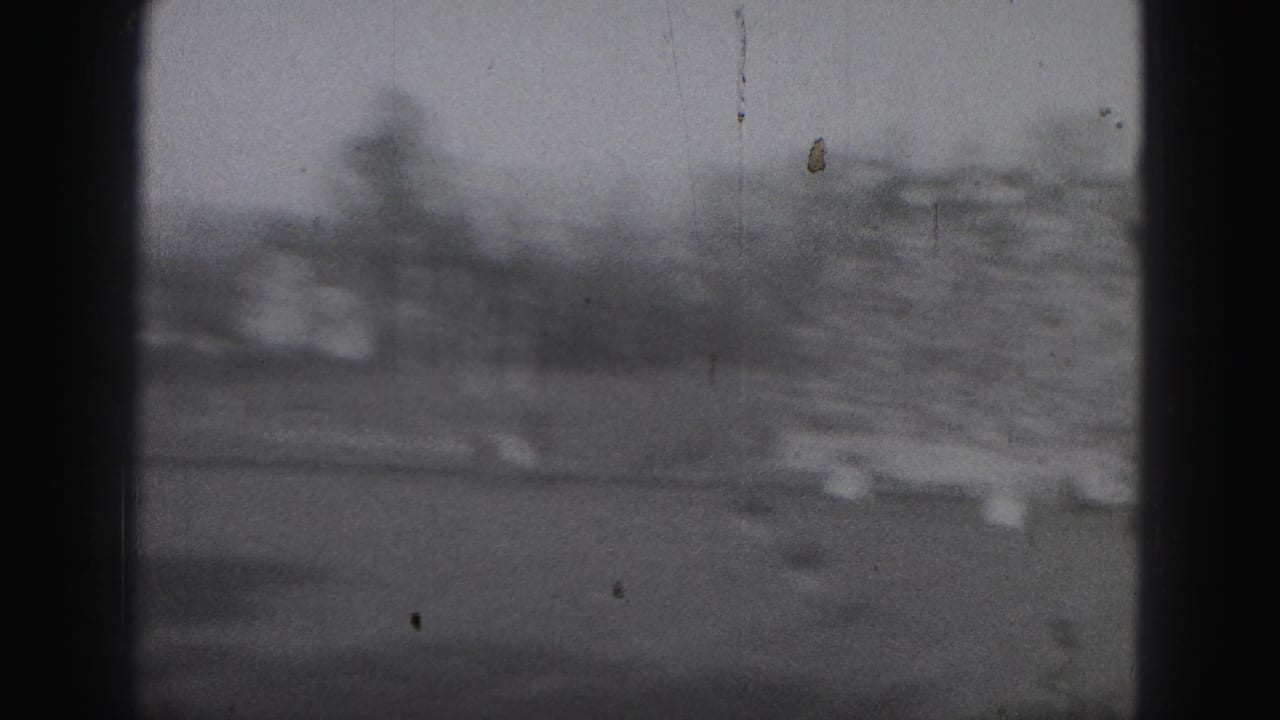 Blurred stadium view with bleachers and football field behind dark vertical film edges.