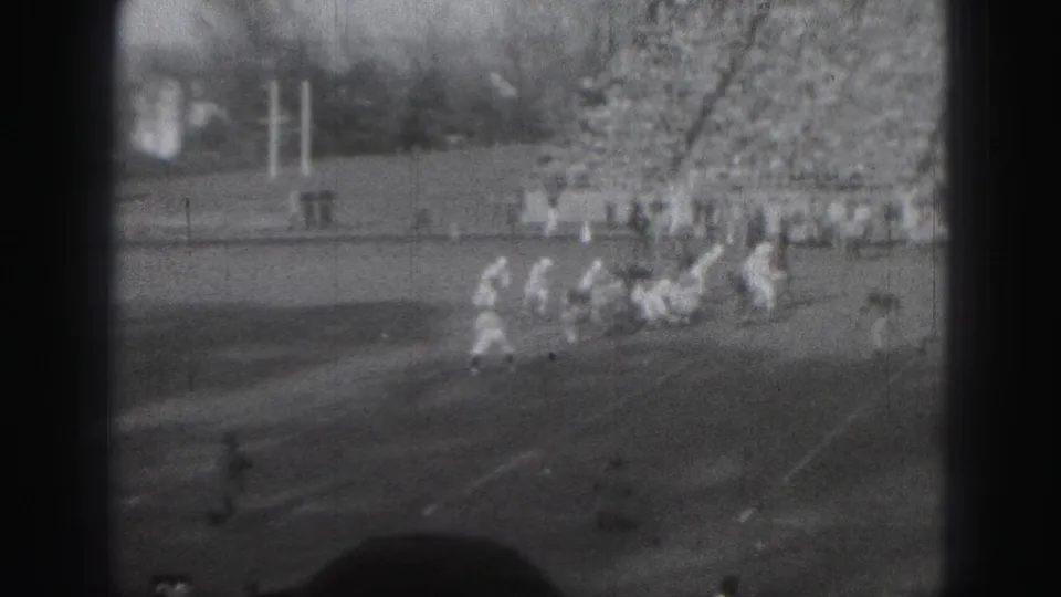 Players in light uniforms cluster near the goal area during a 1946 Harrisburg football sequence, with fans filling the far stands.