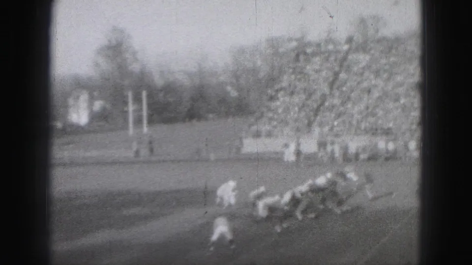 Late play action near the goal area in Harrisburg, with players in motion and a crowded grandstand visible behind them.
