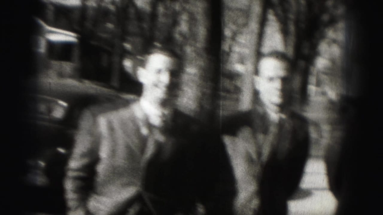 Soft-focused 1946 8mm frame of two suited men standing outdoors on a Harrisburg residential street.