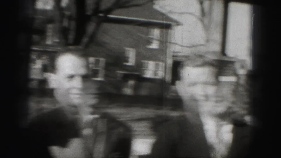 Two adult men in suits appear on a tree-lined Harrisburg residential street in grainy 1946 8mm footage.