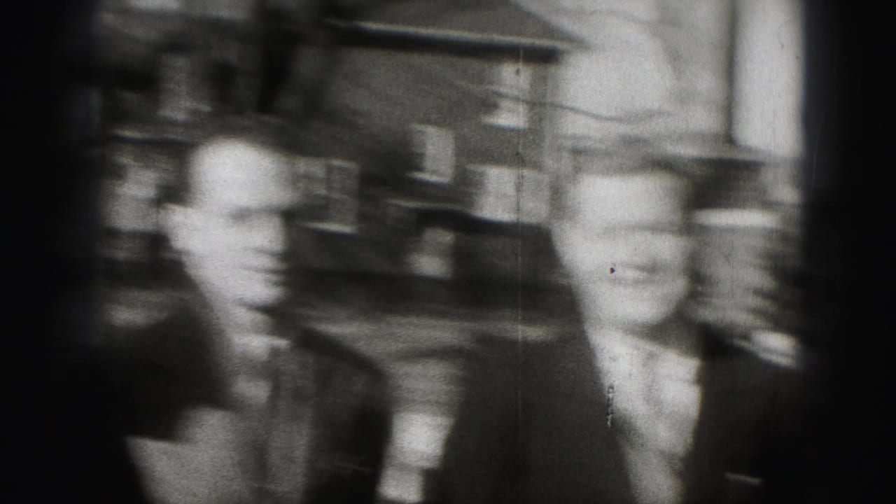 Two suited adult men move through a Harrisburg neighborhood, with brick houses and leafless trees in the background.