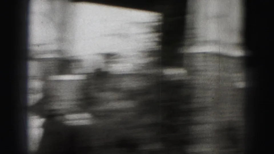 A rapid handheld pan shows a blurred suited figure and indistinct residential street details in 1940s Harrisburg footage.