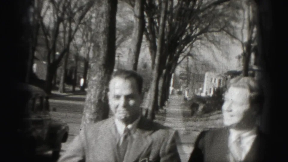 Two adult men in suits stand outdoors on a Harrisburg residential street in 1946 home-movie footage.