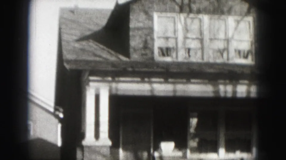 1946 Harrisburg 8mm frame showing a brick residential house with gabled roof, covered porch, columns, and bare branch shadows.