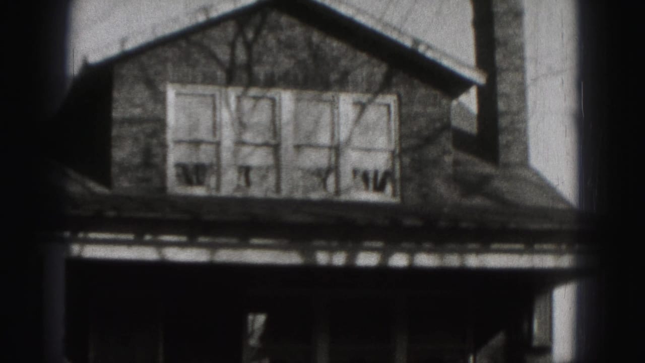 Brick house facade framed tightly with roofline, upper windows, and dark porch.