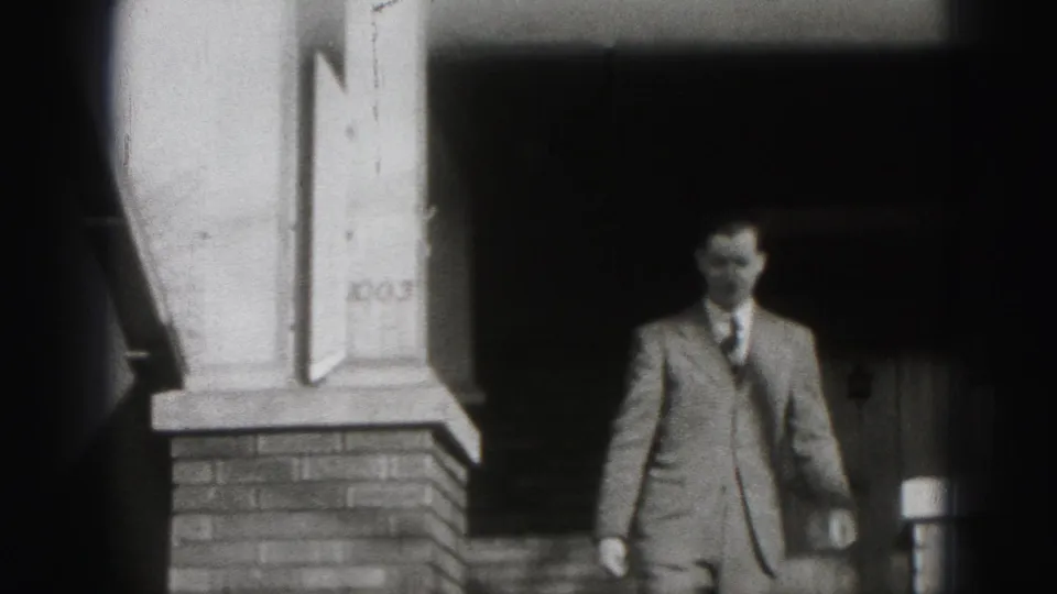 In Harrisburg, Pennsylvania home-movie footage from 1946, a suited man stands near a shaded brick porch marked 1003.