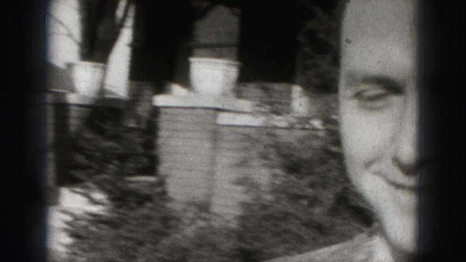 1946 Harrisburg home-movie frame showing a smiling adult man close to the camera near a residential porch, with blur and dark film-edge shadow.