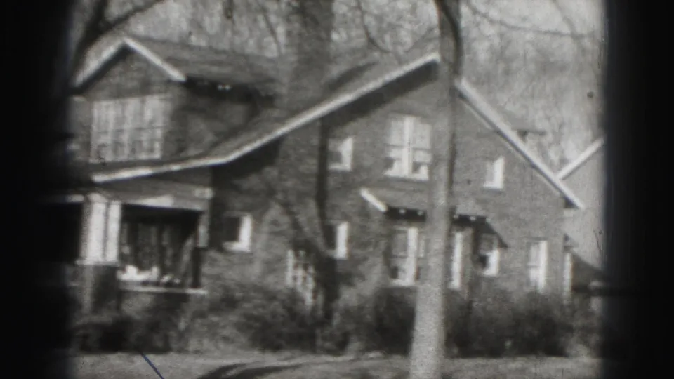 1946 Harrisburg home-movie view of a residential facade with gabled rooflines, windows, trees, shrubs, and visible 8mm vignetting.