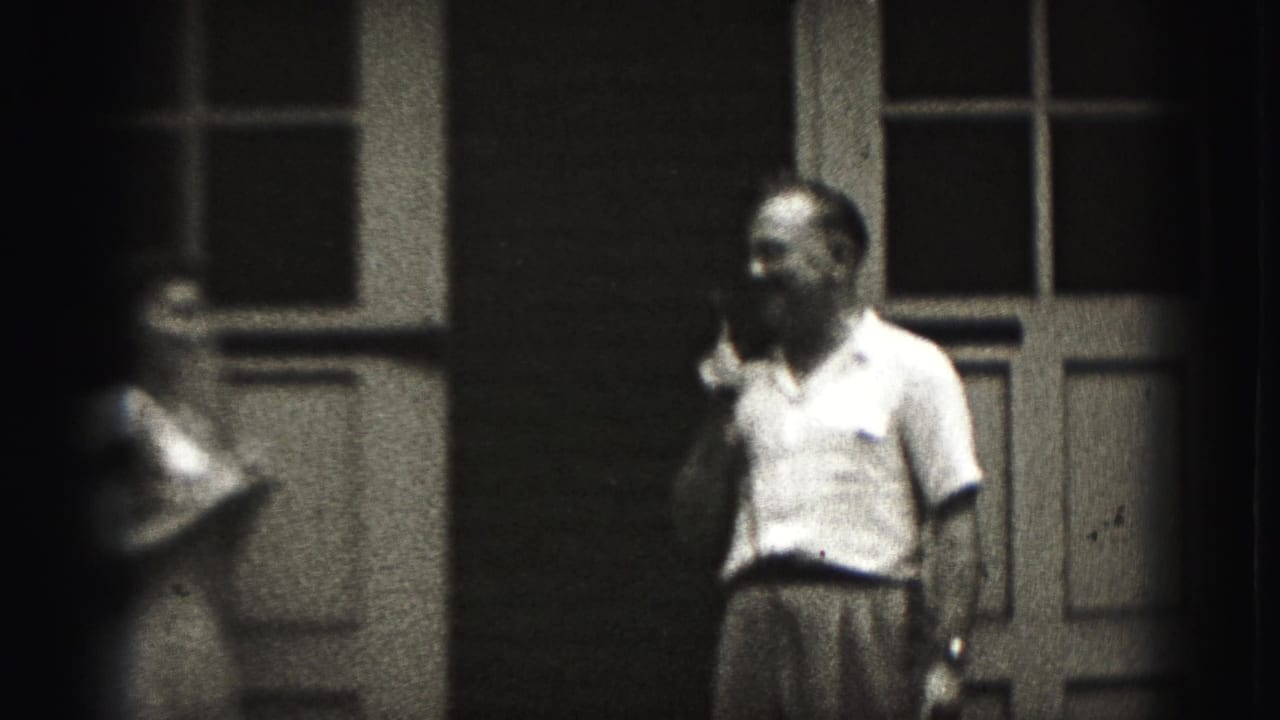 In 1946 New Cumberland home-movie footage, a man with a cigarette faces a woman near paneled exterior doors.