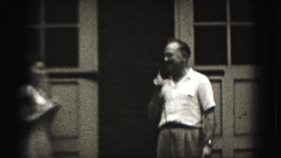 In 1946 New Cumberland home-movie footage, a man with a cigarette faces a woman near paneled exterior doors.