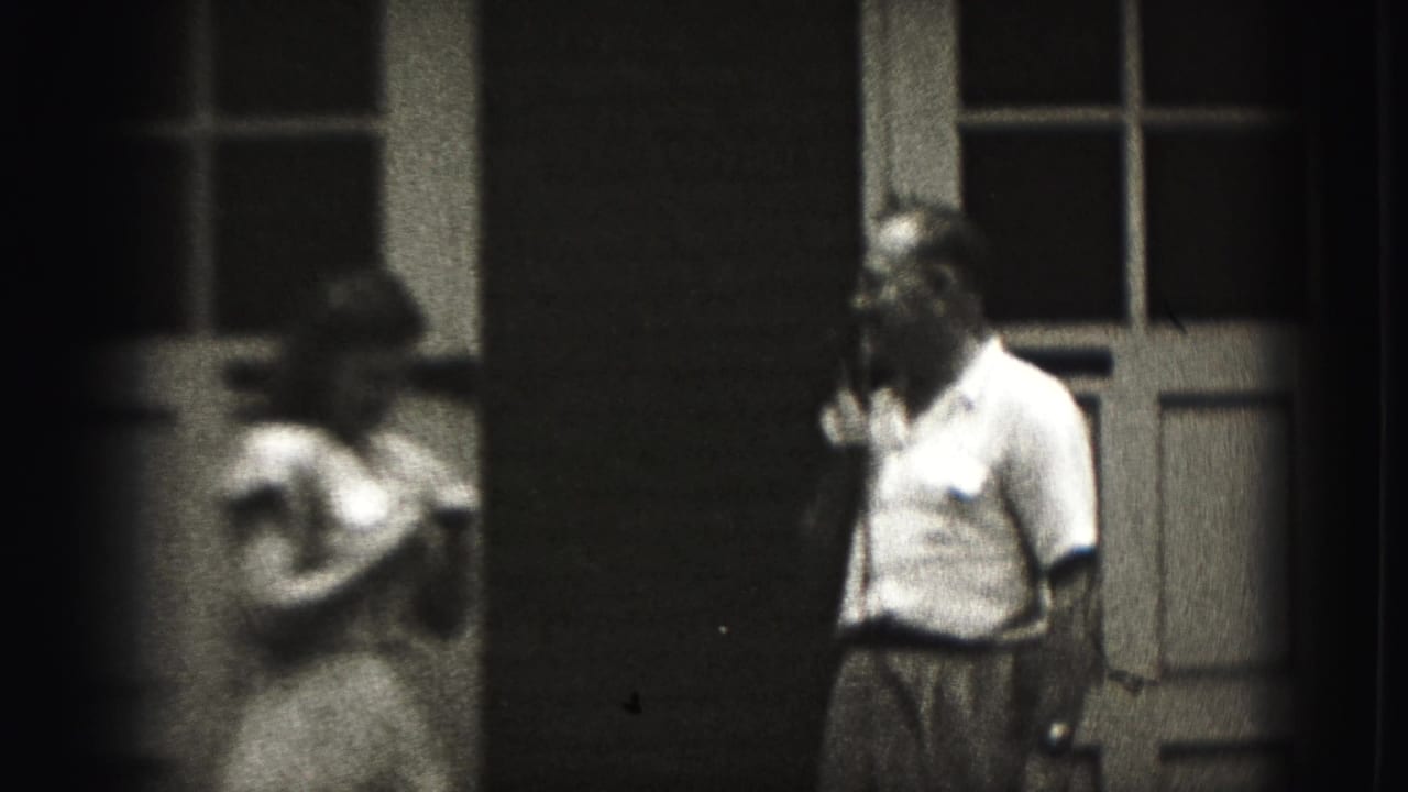 The woman appears blurred in motion while the man remains by the paneled doorway in the New Cumberland exterior scene.