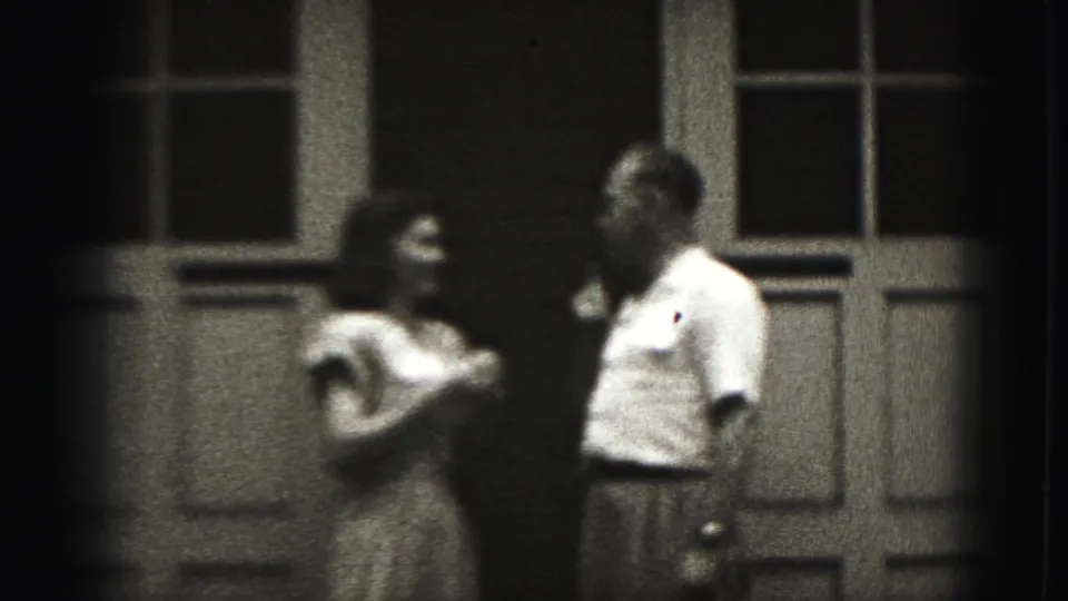 A woman in a light dress and a man in shirt and trousers face each other outside a paneled doorway in New Cumberland, Pennsylvania.