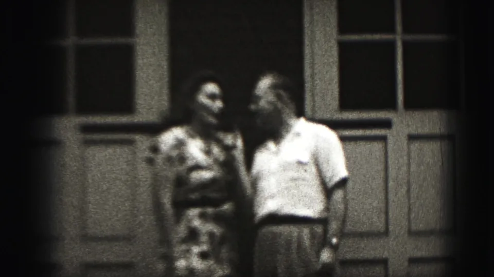 A smiling woman and the man stand close outside the doorway, ending the short 1946 New Cumberland domestic phone-call scene.