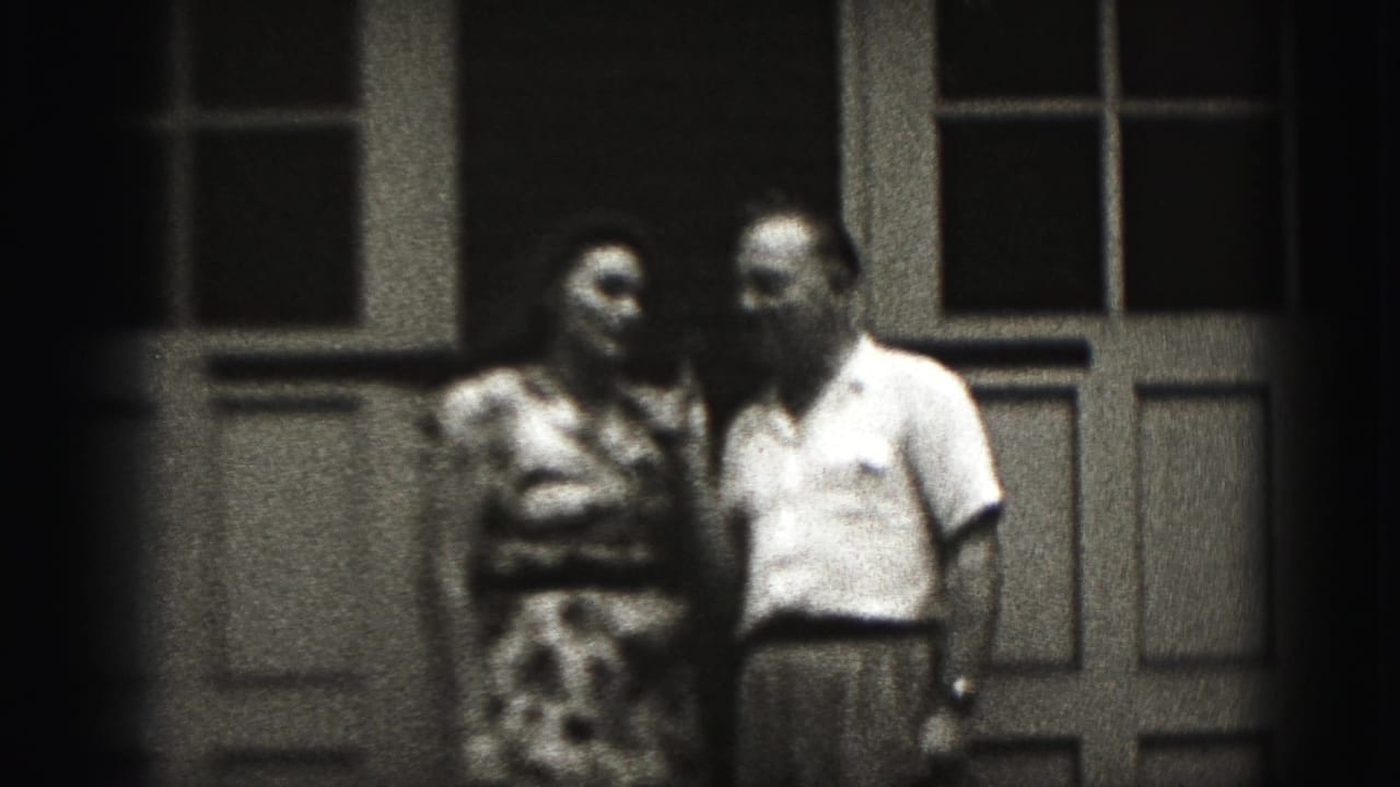 Adult couple standing close together outside a door and window.