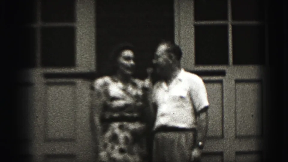 The final frame holds on the adult couple outside the New Cumberland doorway, with visible 8mm grain and dark edge falloff.