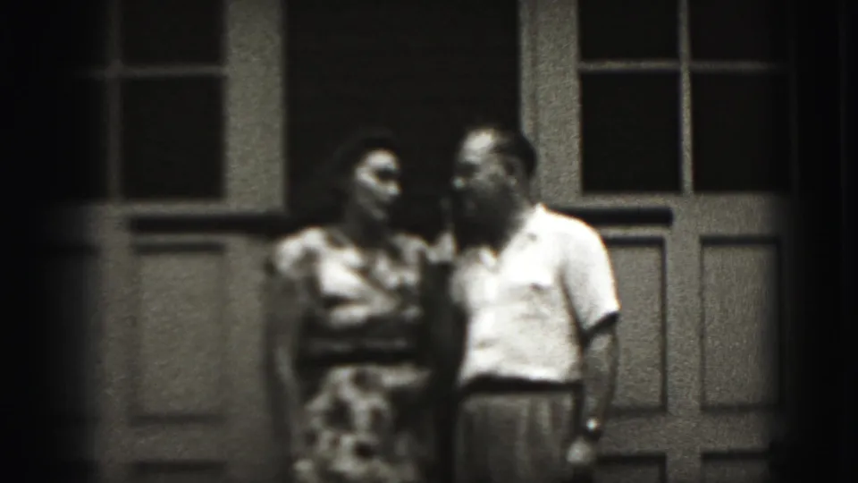 The 1946 home-movie frame shows the couple turned toward one another on a New Cumberland porch, with soft focus and dark edges.